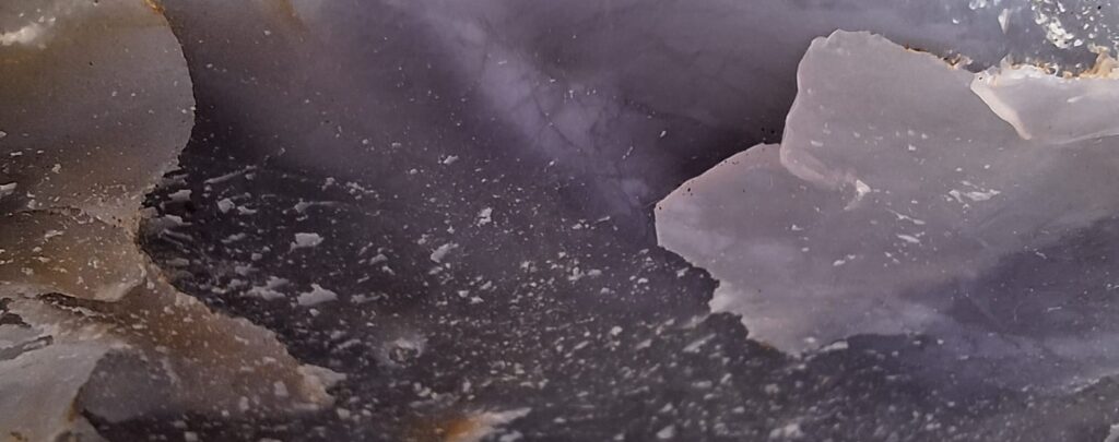 Superficie de calcedonia gris en vista macro, mostrando vetas y texturas naturales