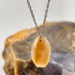 Colgante de Calcedonia naranja, cortada en facetas, colgando de una cadena de acero inoxidable.